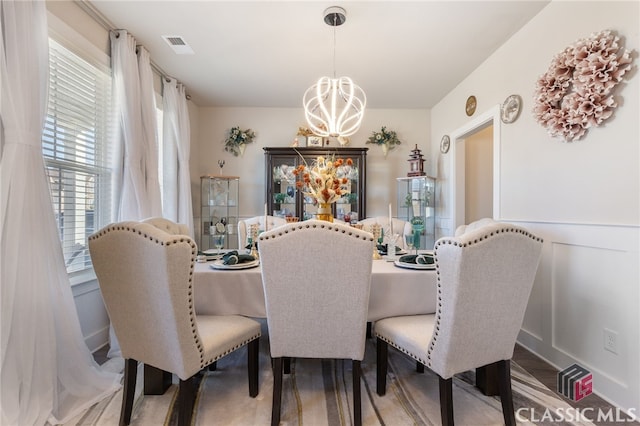 dining space featuring an inviting chandelier, wood finished floors, and visible vents