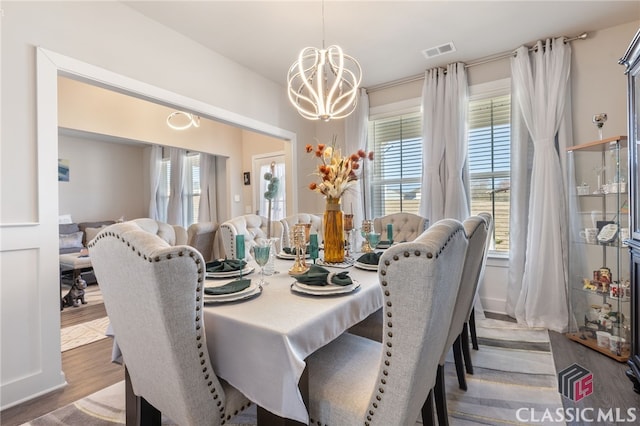 dining room featuring an inviting chandelier, plenty of natural light, wood finished floors, and visible vents