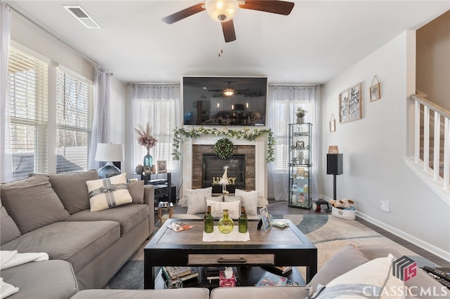 living room featuring a high end fireplace, visible vents, a wealth of natural light, and ceiling fan