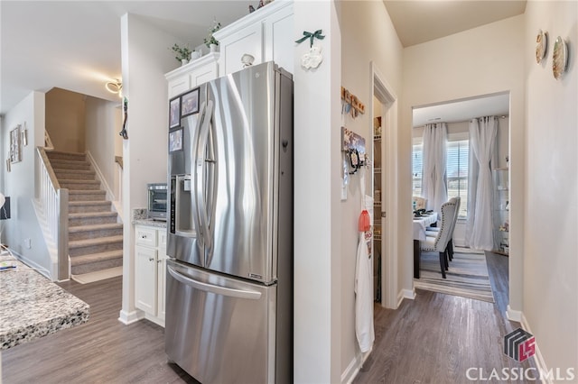 kitchen with dark wood finished floors, stainless steel fridge, white cabinetry, and baseboards