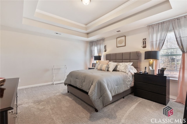 bedroom with a tray ceiling, baseboards, visible vents, and crown molding