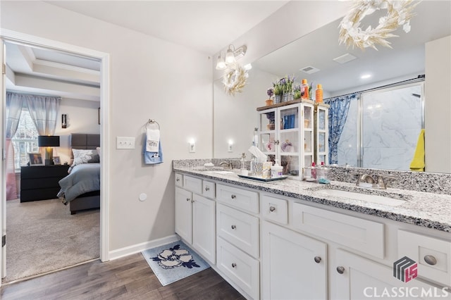 full bathroom featuring double vanity, wood finished floors, a shower with door, and a sink