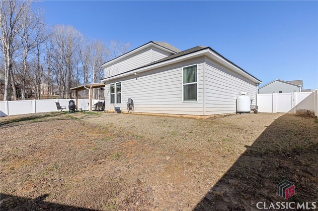 rear view of property with a yard and a fenced backyard