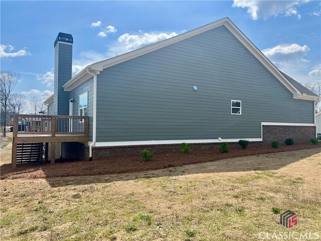 view of side of home featuring a deck, stairs, and a chimney