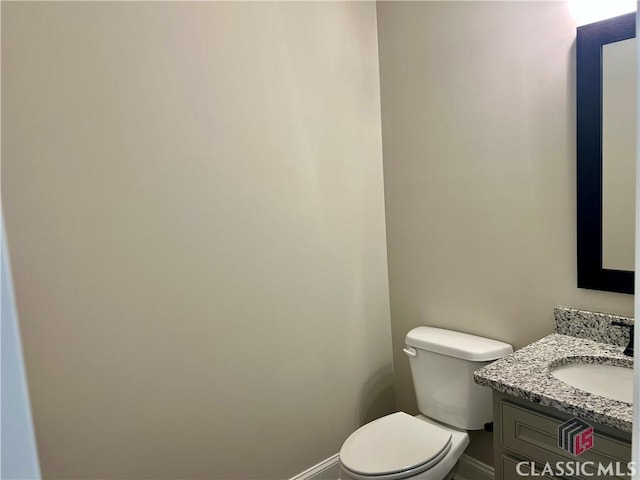 bathroom featuring toilet, vanity, and baseboards