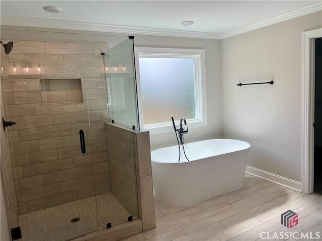 full bath featuring wood finished floors, baseboards, a soaking tub, a shower stall, and crown molding