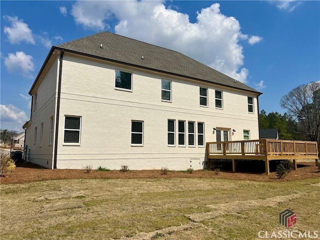 back of property with a deck, a lawn, brick siding, and crawl space