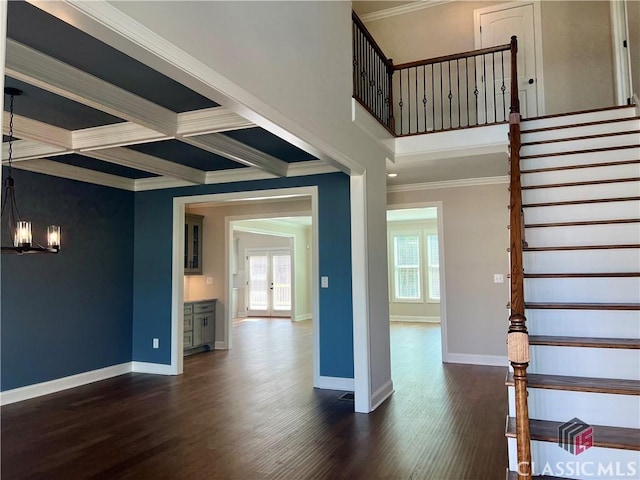 interior space with crown molding, baseboards, a high ceiling, an inviting chandelier, and wood finished floors