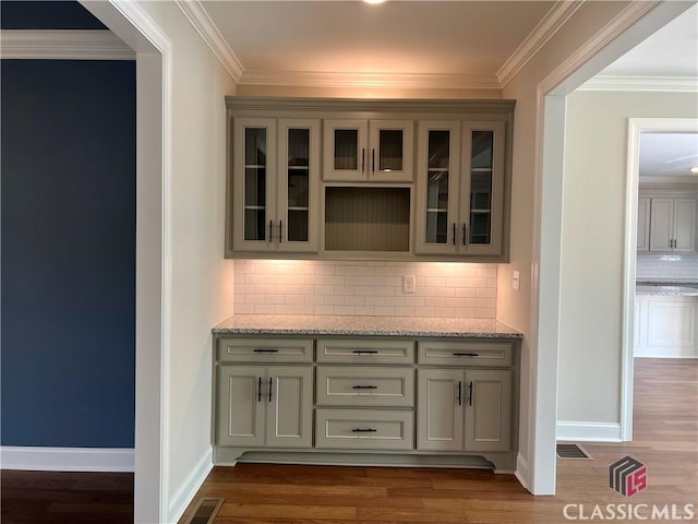 interior space featuring visible vents, crown molding, and wood finished floors