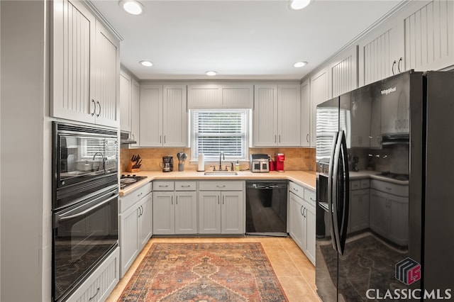 kitchen featuring black appliances, light countertops, backsplash, and a sink