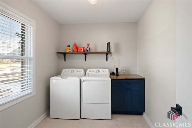 washroom featuring light tile patterned floors, baseboards, cabinet space, and washing machine and dryer