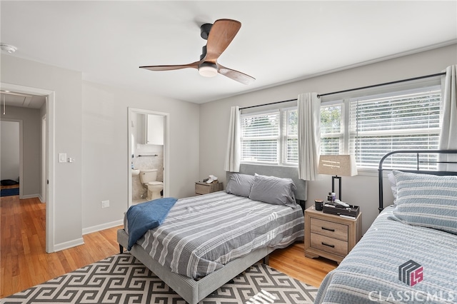 bedroom with baseboards, attic access, light wood-type flooring, ensuite bathroom, and a ceiling fan