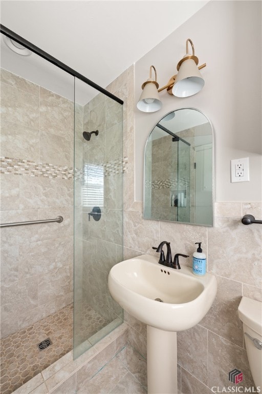 bathroom with a shower stall, toilet, and tile walls