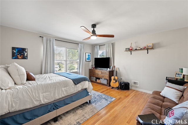 bedroom with light wood finished floors, visible vents, ceiling fan, and baseboards