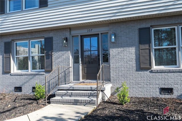 doorway to property with crawl space and brick siding