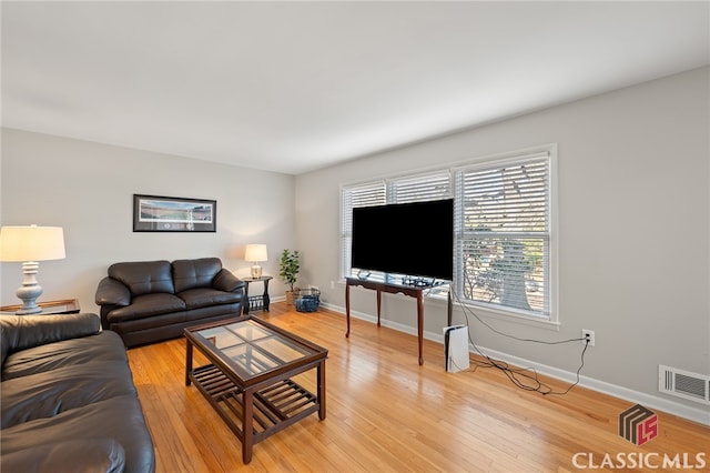 living room with visible vents, baseboards, and light wood finished floors