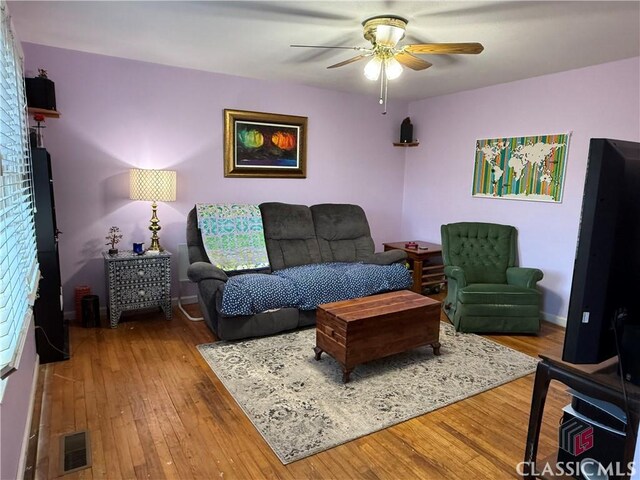 living area featuring visible vents, baseboards, a ceiling fan, and hardwood / wood-style floors