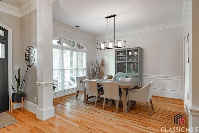 dining area with visible vents, light wood-style flooring, wainscoting, crown molding, and a chandelier