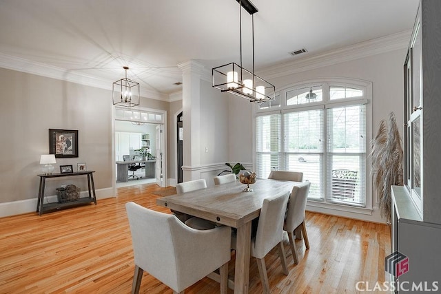 dining space with light wood-type flooring, visible vents, a chandelier, and crown molding