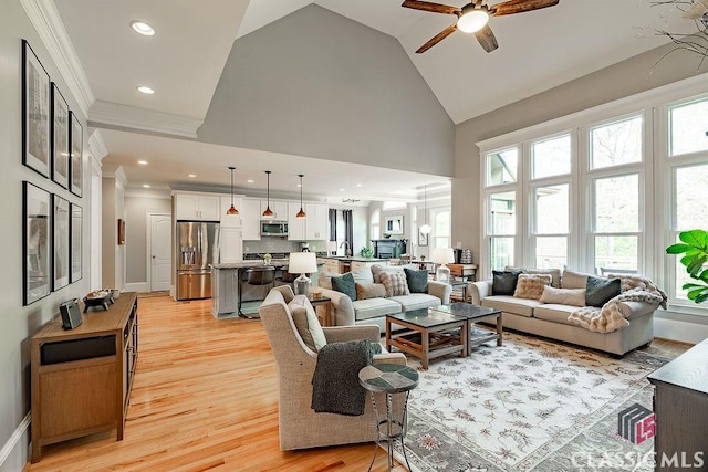 living area featuring light wood finished floors, ornamental molding, recessed lighting, high vaulted ceiling, and a ceiling fan