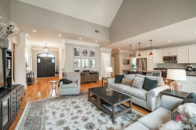 living area with recessed lighting, visible vents, light wood-style flooring, and decorative columns