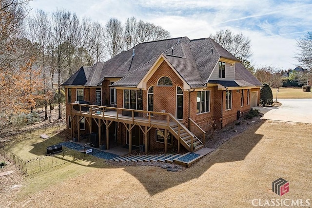 back of house with fence, driveway, stairs, a deck, and brick siding