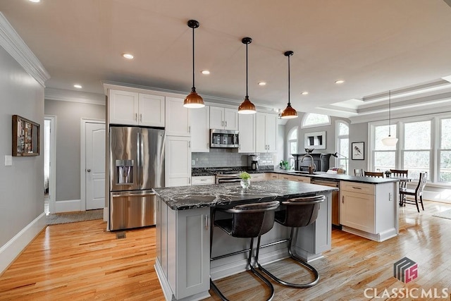 kitchen with a peninsula, a sink, appliances with stainless steel finishes, tasteful backsplash, and a center island