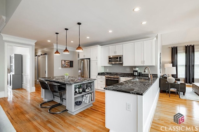 kitchen featuring a sink, open shelves, white cabinetry, a barn door, and appliances with stainless steel finishes