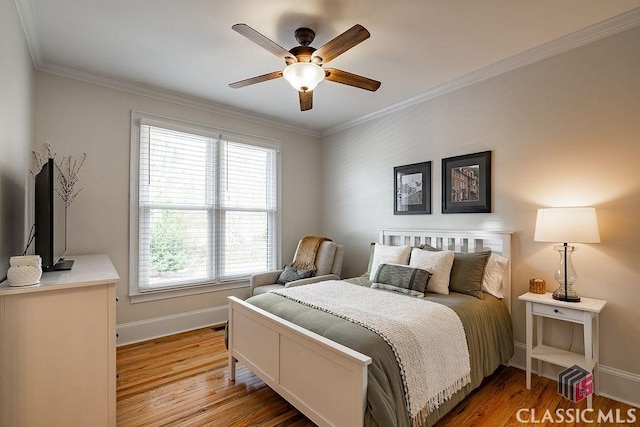 bedroom featuring light wood finished floors, ceiling fan, baseboards, and ornamental molding