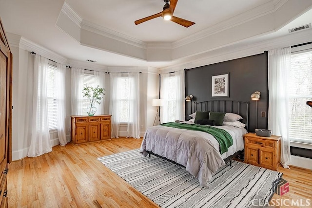 bedroom with visible vents, multiple windows, and a tray ceiling