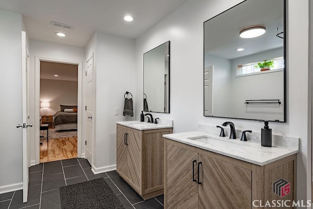 ensuite bathroom with two vanities, connected bathroom, visible vents, and a sink