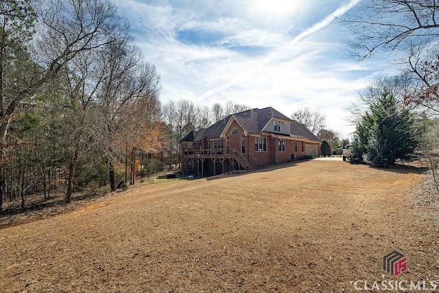 back of property with stairway, a lawn, a wooden deck, and an attached garage