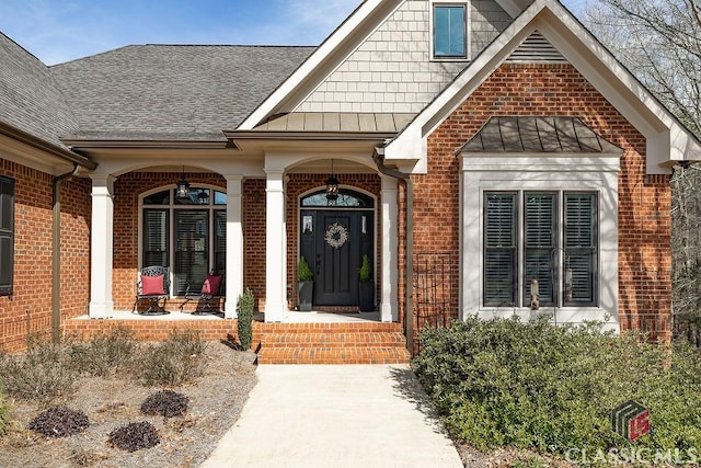 property entrance with a standing seam roof, brick siding, and a shingled roof