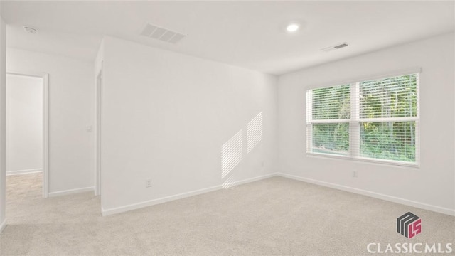 spare room with visible vents, baseboards, and light colored carpet