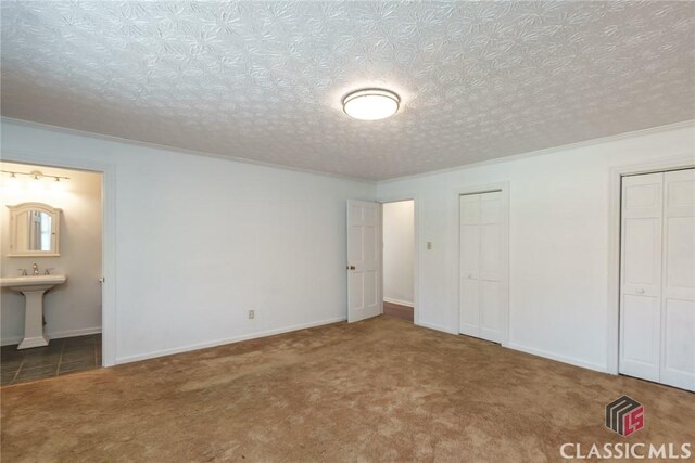 1050 Eugene Ln, Madison, GA 30650 - unfurnished bedroom featuring connected bathroom, carpet flooring, a textured ceiling, baseboards, and two closets