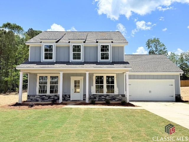 traditional-style house featuring an attached garage, board and batten siding, a front lawn, and concrete driveway