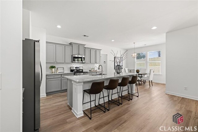kitchen with visible vents, a sink, a kitchen bar, stainless steel appliances, and gray cabinets