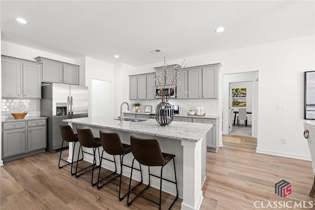 kitchen featuring an island with sink, a sink, appliances with stainless steel finishes, and gray cabinetry
