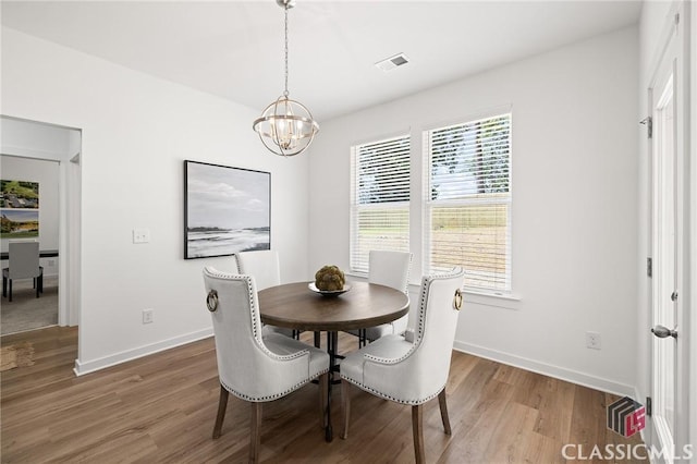 dining space with baseboards, a chandelier, wood finished floors, and visible vents