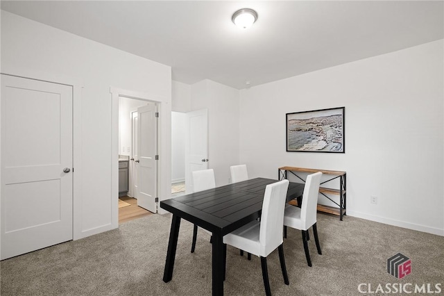 dining room featuring light colored carpet and baseboards