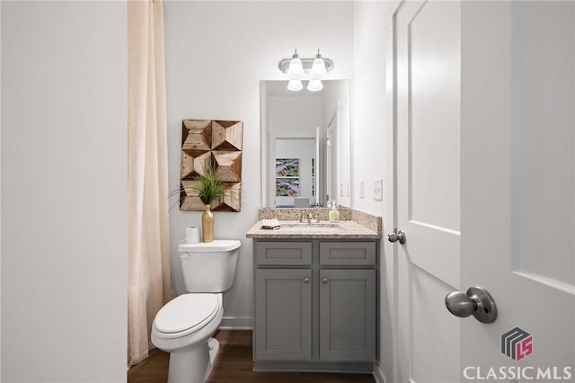 bathroom with toilet, baseboards, wood finished floors, and vanity