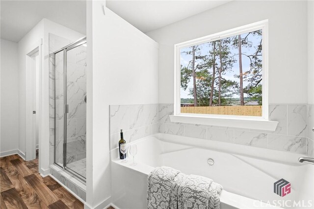 bathroom with a marble finish shower, a garden tub, and wood finished floors