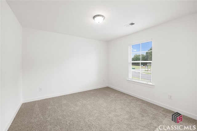 carpeted empty room featuring baseboards and visible vents