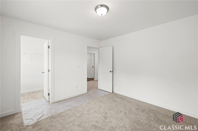 unfurnished bedroom with baseboards, a spacious closet, and carpet floors