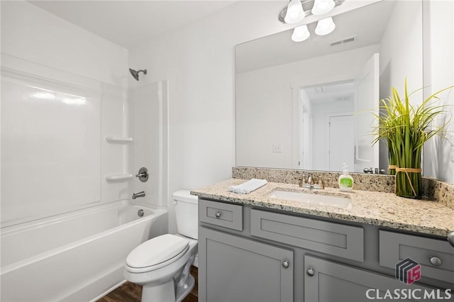 bathroom featuring toilet, visible vents, shower / tub combination, vanity, and wood finished floors