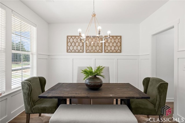 dining room featuring a wainscoted wall, a chandelier, a decorative wall, and dark wood-type flooring