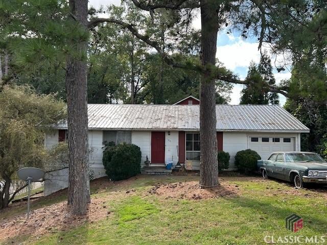ranch-style home featuring an attached garage, a front lawn, and metal roof