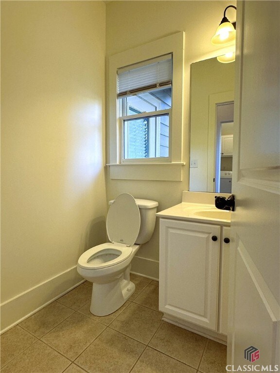 bathroom featuring baseboards, toilet, tile patterned flooring, and vanity