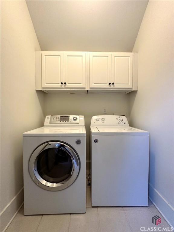 laundry room featuring baseboards, cabinet space, independent washer and dryer, and light tile patterned floors