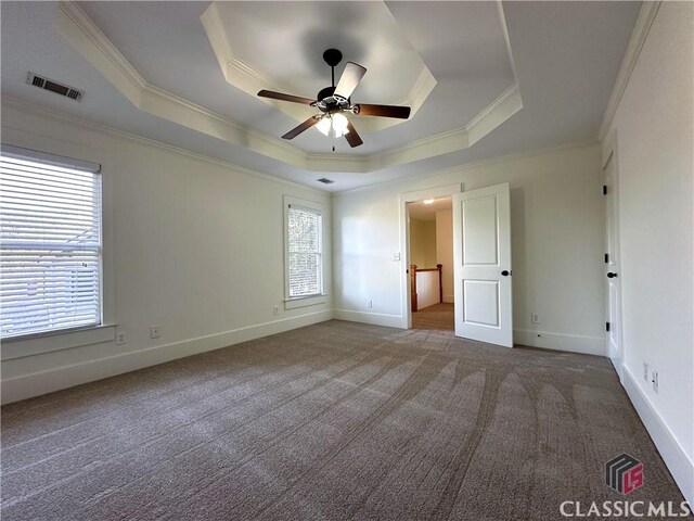 unfurnished bedroom featuring a raised ceiling, carpet floors, crown molding, and visible vents